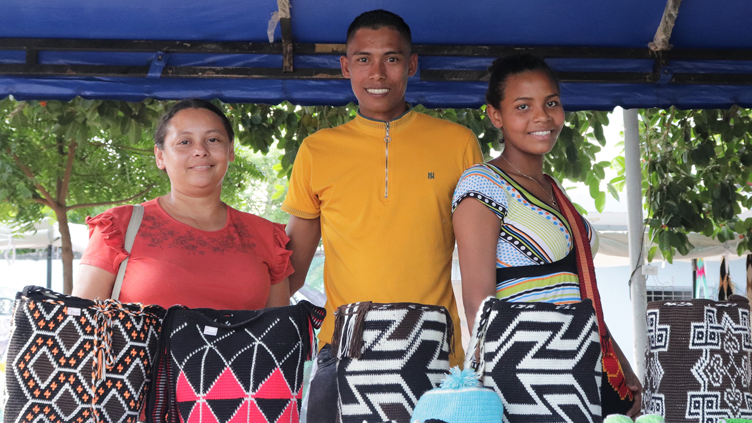 Tres artesanos frente a sus mochilas tejidas durante la feria de artesanias del festival de Gaitas 2022